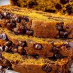 Moist chocolate chip pumpkin bread slice on a wooden table