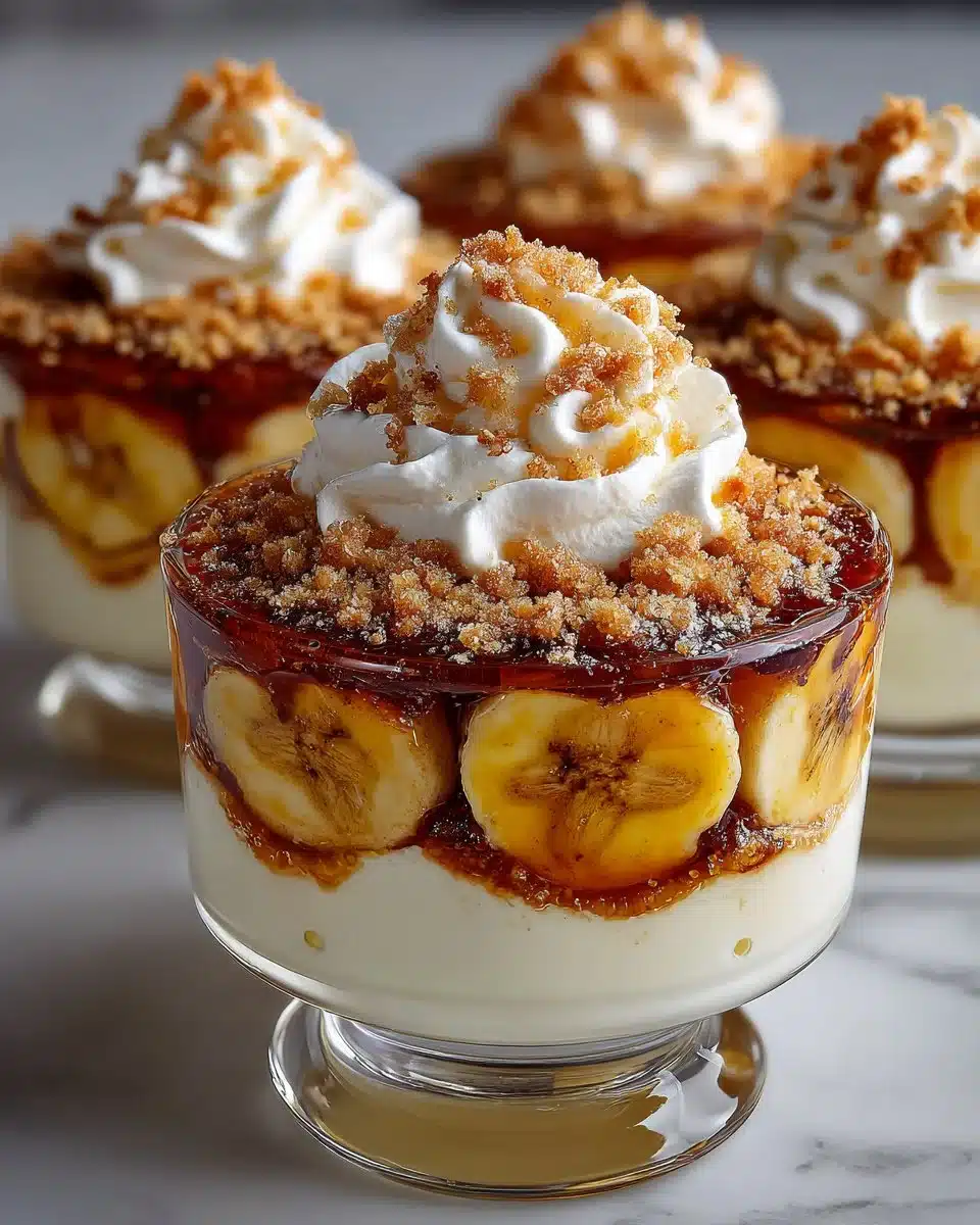 Caramelized banana pudding cups topped with fresh bananas and whipped cream